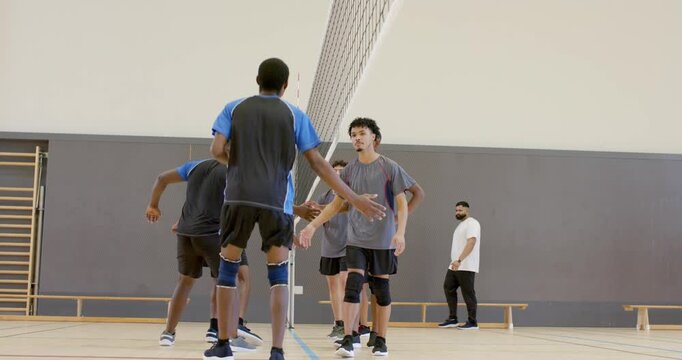 Opposing volleyball teams moving to net postmatch exchanging handshakes displaying fair play in gym