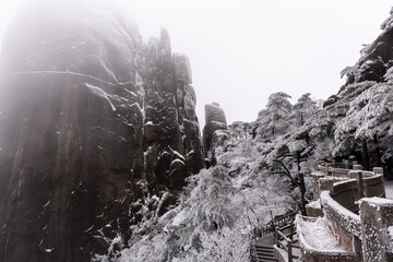 Huangshan, China: Hiking path by the cliff in the frozen landscape of the Yellow mountain in Mount Huangshan in China in winter