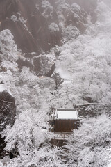 Mt Huangshan, China: Mystic view of a ancient temple by a cliff in the frozen landscape of the Yellow mountain in Mt Huangshan in China in winter