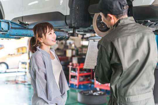 A female customer and a male mechanic receive an explanation about car maintenance and inspection at a repair shop