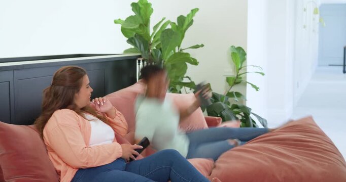 African American women friends on rose sofa at home scrolling phones hallway entry sparking sharing