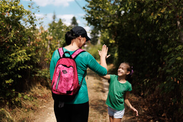 Naklejka premium Mother and daughter sharing a joyful moment during an outdoor hike in a forest trail