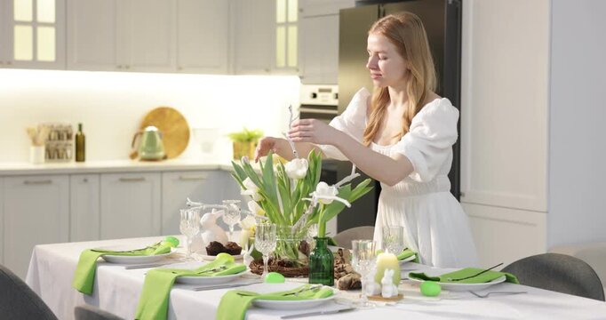 Woman setting festive table for Easter celebration at home