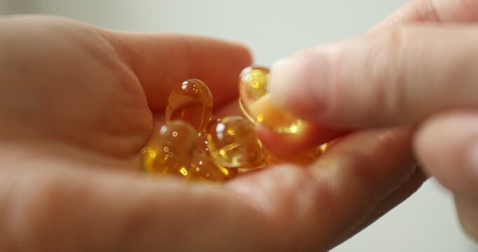 Woman holding pile of gelatin capsules on light background, closeup