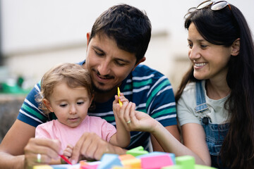 Obraz premium Happy family enjoying creative playtime together with their young child outdoors