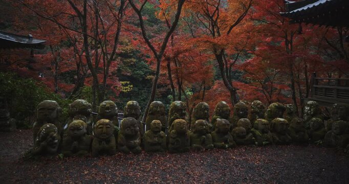 Rows of moss covered buddha statues in ancient Japanese village during autumn season