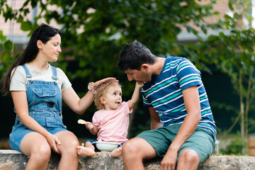 Fototapeta premium Mother, Father, and Toddler Enjoying Quality Time Together Outdoors on a Warm Day
