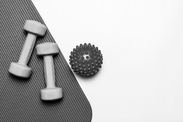 Fitness essentials dumbbells, massage ball, yoga mat. Clean flat lay with ample copy space for workout, health and wellness content