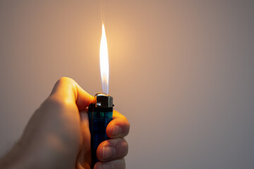 A person is holding a lighter with a blue flame