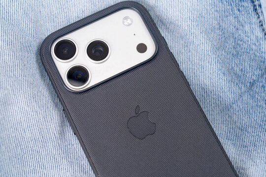 Bar, Montenegro: February 6, 2026: new white Apple iPhone 17 PRO with black case lies face down on light blue denim, revealing its triple camera module and Apple logo through matte protective cover
