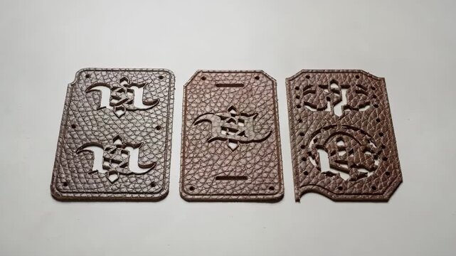 Medium shot capturing lasercut leather panels embossed with stylized logos illustrating custom branding and detailed precision in luxury accessory creation.