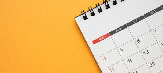 Top view of spiral desk calendar on bright orange background with large copy space for schedule and...
