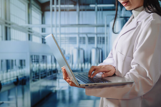 Asian young female quality control specialist holding a tablet in a modern dairy factory, approving production standards, ensuring food safety,hygiene compliance,smart manufacturing, industrial