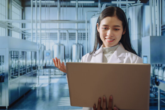 Asian young female quality control specialist holding a tablet in a modern dairy factory, approving production standards, ensuring food safety,hygiene compliance,smart manufacturing, industrial