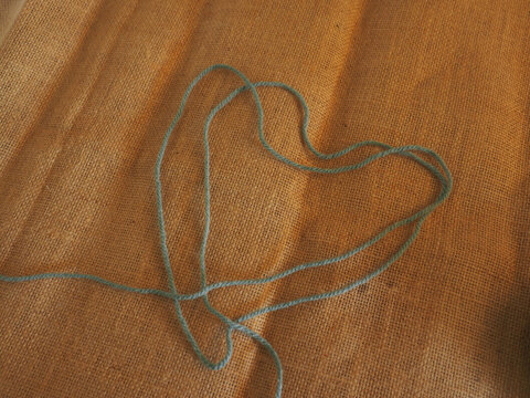 Ball of yarn placed on brown burlap fabric, captured in warm natural light. Rustic textures and cozy tones create a comforting handmade atmosphere, perfect for craft projects, knitting hobbies