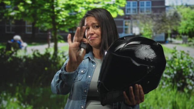 Woman holding black helmet and showing keys between fingers with her hand in front of a building; frustration inconvenience.