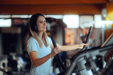 Fototapeta premium Smiling Woman Exercising at the Gym on an Elliptical Bike. Cheerful gym girl training on a cross trainer at a fitness center