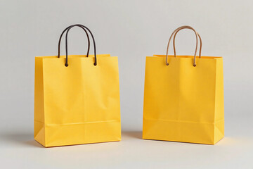 Two bright yellow paper shopping bags with black handles on grey background.