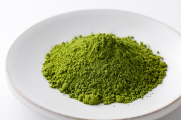 Fototapeta premium 白背景に置かれた鮮やかな日本の抹茶パウダー Premium organic Japanese matcha powder, healthy superfood and antioxidant green tea