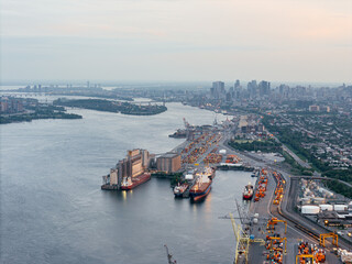 Obraz premium Aerial view of Montreal port with cargo containers, cranes and city skyline at sunset. g.