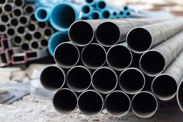 A stack of black pipes with blue pipes in the background