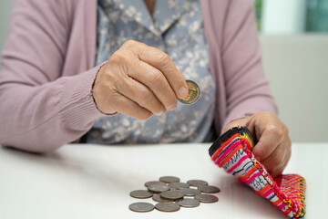 Asian senior or elderly old lady woman holding counting coin money in bag. Poverty, saving problem in retirement.