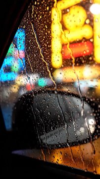 Raindrops on a car window at night with blurred city lights creating a vibrant