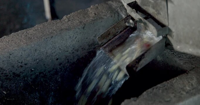 Industrial Slurry Discharging From Metal Chute Into Processing Tank At Manufacturing Plant