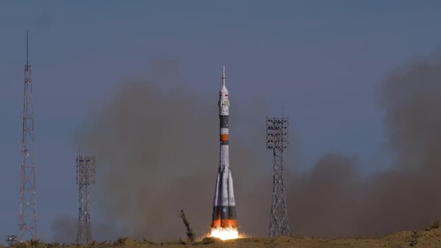 A Soyuz rocket launches from the launchpad, ascending into the sky. Engines ignite with smoke and fire.
