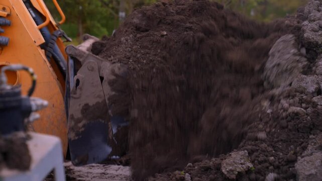 Nutrient rick soil scooped on a fruit orchard, bobcat scooping into tractor trailer spreading machine