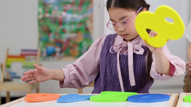 Asian Girl Learning Mathematics with Colorful Foam Number Puzzles in Classroom