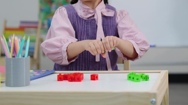 Young Girl in Purple Dress Playing with Colorful Connecting Cubes