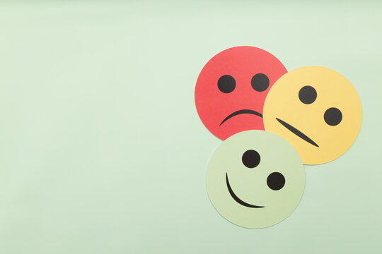 Customer satisfaction survey icons with sad, neutral, and happy faces on a green background. Concept for business feedback, rating, review, and mental health assessment. Minimalist flat lay.