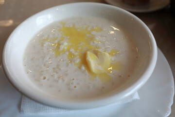 Milk porridge with melted butter in white bowl