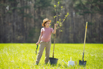 Kid cultivating tree with shovel. Kid cultivating tree on backyard. Kid cultivating tree in spring field. Little gardener with watering can and shovel. Kid cultivating tree on garden farm. Kids work. © Volodymyr