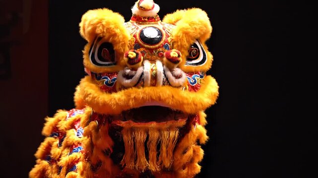 A close-up shot of a vibrant lion dance head with intricate designs, performed during a traditional celebration, with a dark background
