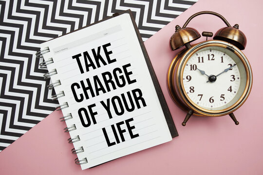 Take Charge Of Your Life text written on notepad with alarm clock