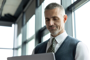 Fototapeta premium Remote online working. Business success. Adult businessman using laptop in business office. Freelancer working online. Man CEO negotiating online. Businessman in suit with laptop in office