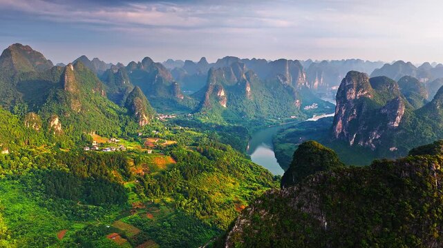 Aerial view of the winding Li River flowing through karst mountain peaks during a beautiful sunrise in Guilin, China.