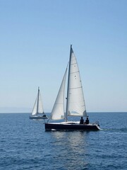 Fototapeta premium Two Sailboats Gliding Across Calm Blue Ocean Under Clear Sky During Daytime Sailing Adventure On Tranquil Waters