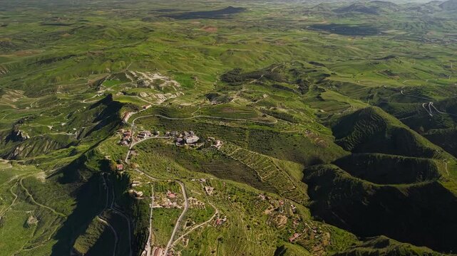 Aerial view over small Centuripe community properties on lush Enna province mountain valley hilltops