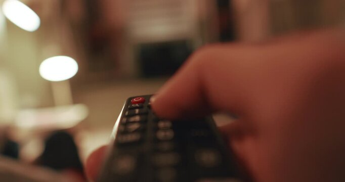 Remote turning TV on from seated POV, calm indoor setting