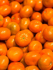A pile of oranges with one of them being slightly smaller than the others