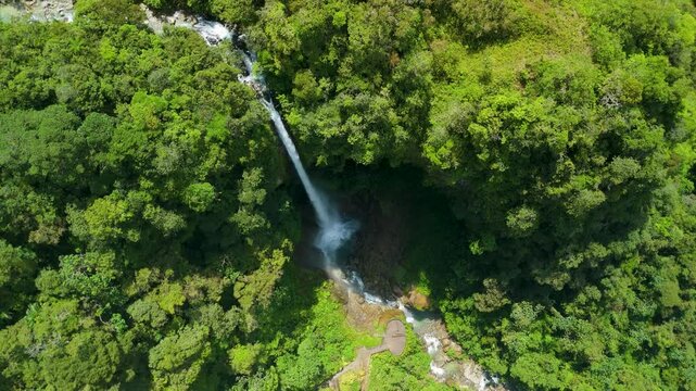 Overhead drone parallax shot circling the white waters of Cascada El Rocio Machay as it plunges into a tropical basin surrounded by dense Andean rainforest in Ecuador