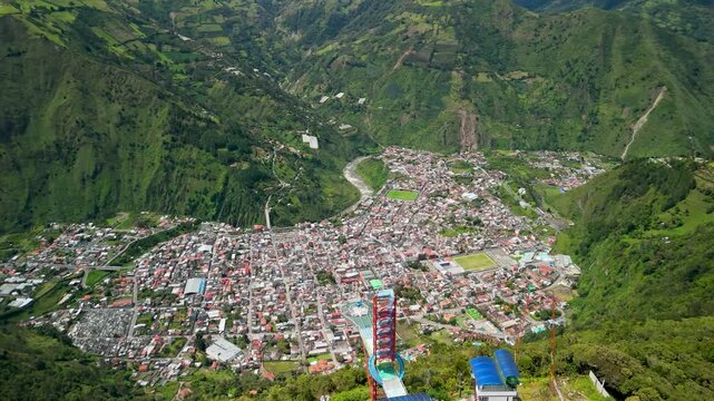 Dynamic aerial parallax circling the modern Pasarela Diamante skywalk structure with panoramic views of Banos de Agua Santa city and the green Andean valley in Ecuador
