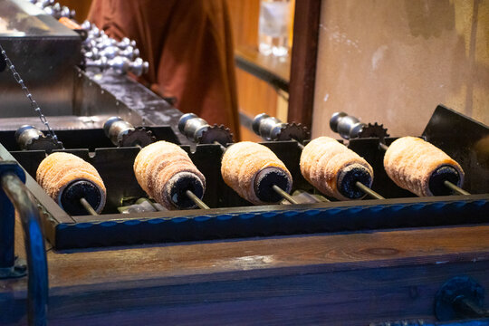 Close-up detail of traditional Czech trdeln&iacute;k pastries displayed side by side. Sweet chimney cakes with golden crispy crust, covered in sugar and nuts, freshly baked and ready to eat. 
