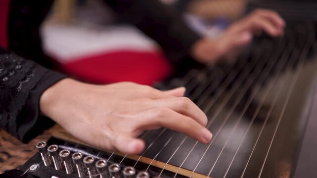 Closeup hands plucking Sundanese kacapi string instrument