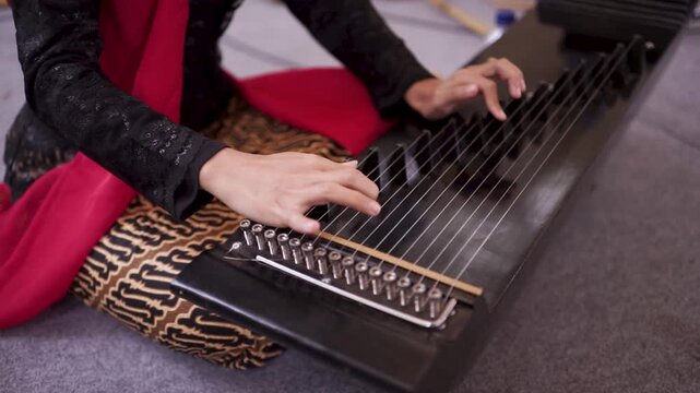 Sundanese musician playing traditional kacapi instrument closeup