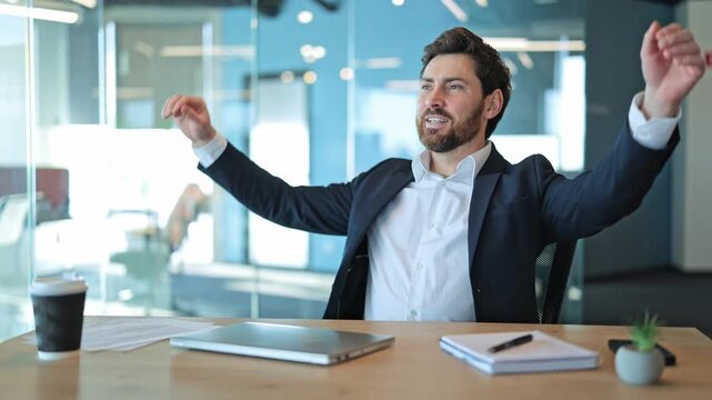 Professional finishes task, closes laptop. Content individual stretches arms, relaxes in chair. Feels satisfaction happiness after productive work, enjoying moment of accomplishment in bright office.