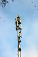 a city communication tower, blue sky, tree branches, daytime